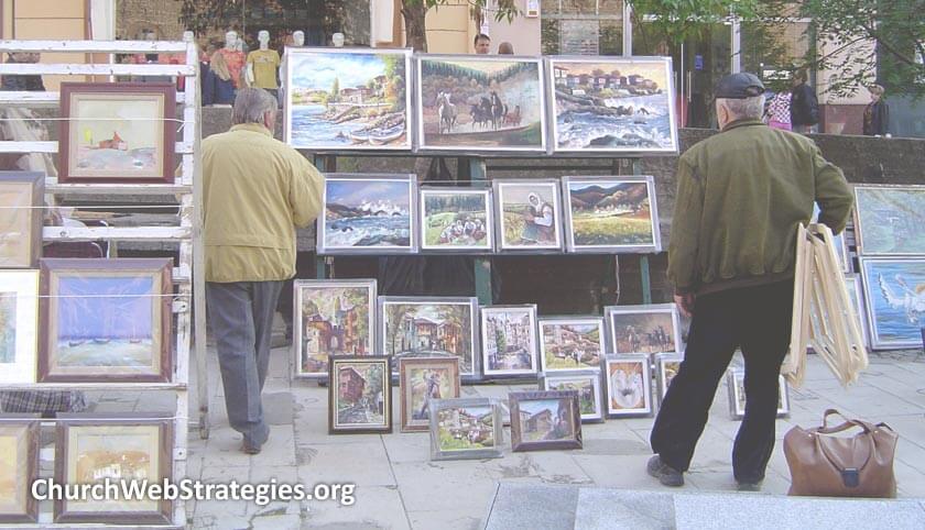 men browsing paintings at street-side sale
